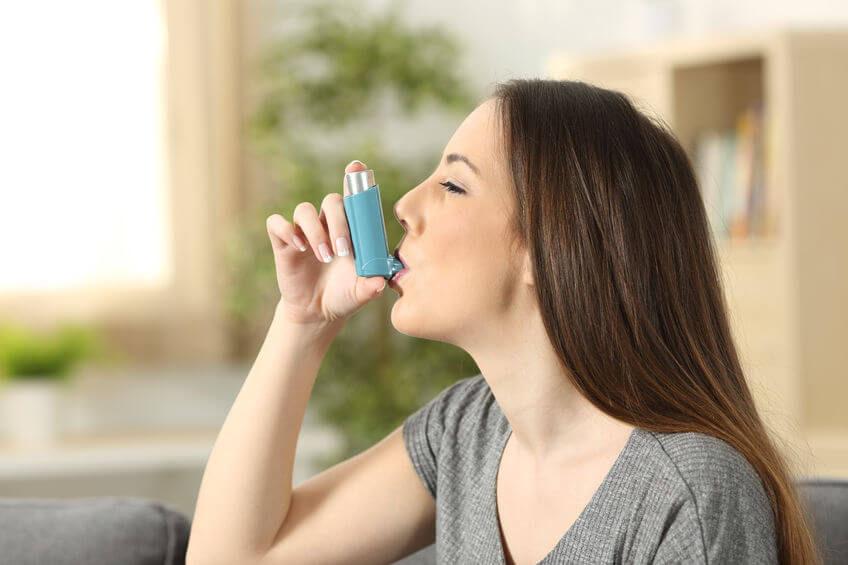 A young woman using an inhaler.